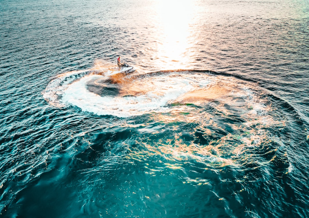 A sleek jet boat gliding across a clear blue lake, showcasing its streamlined design and water-jet propulsion system.